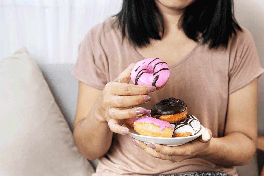 a woman holds a dish of donuts