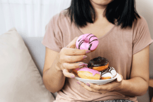 a woman holds a dish of donuts