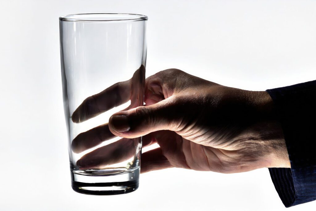 a hand holds an empty beer glass